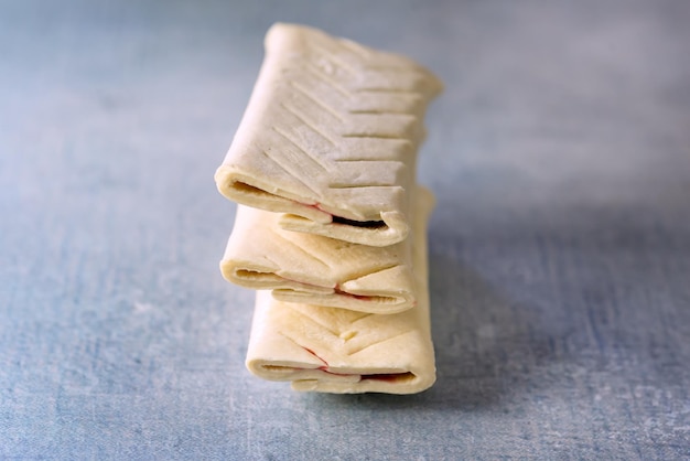 Stratificato di una torta di pasta francese soffice cruda di panini crudi con marmellata su sfondo blu