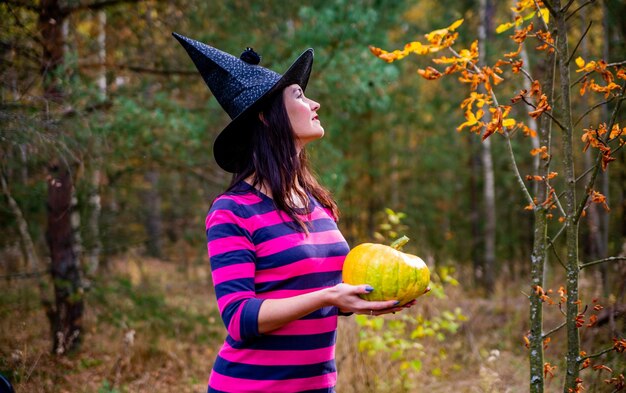 Strega con piccola zucca nella foresta d'autunno