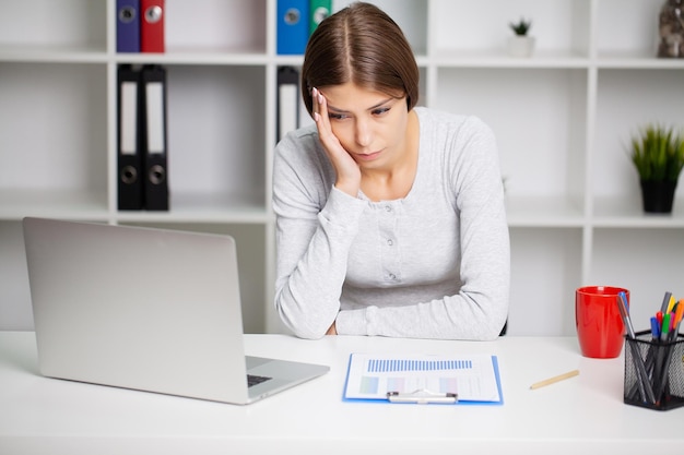 Stressato Donna D'affari Tenendo La Testa Con La Mano In Ufficio