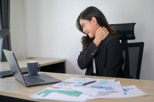 Stressato giovane donna d'affari che lavora al computer portatile con documenti nel moderno concetto di carico di lavoro dell'ufficio