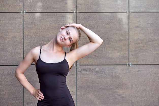 Stretching fitness donna o ginnasta o ballerino che fa esercizi su sfondo urbano della città del muro grigio