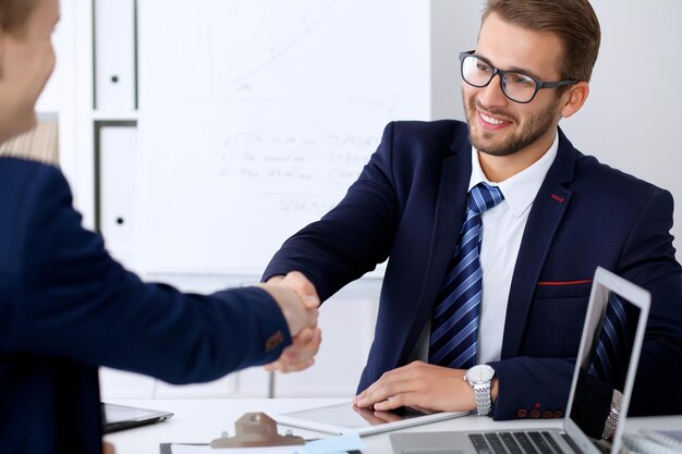 Stretta di mano d'affari durante la riunione o la negoziazione in ufficio. I partner sono soddisfatti perché firmano contratto o documenti finanziari.