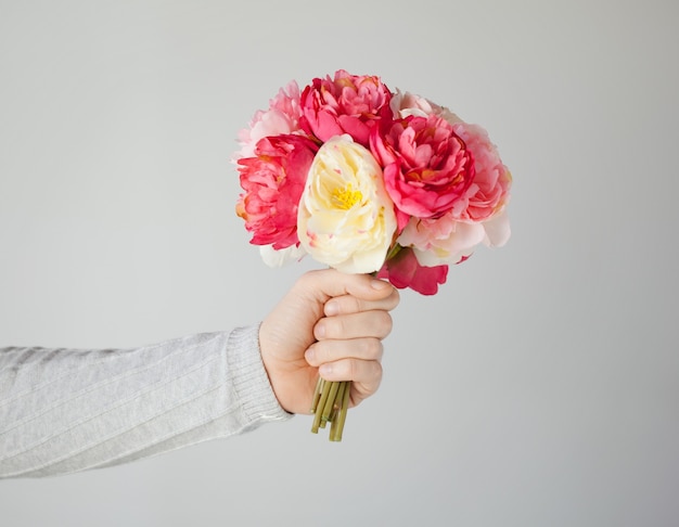 stretta di mano d'uomo dando mazzo di fiori.