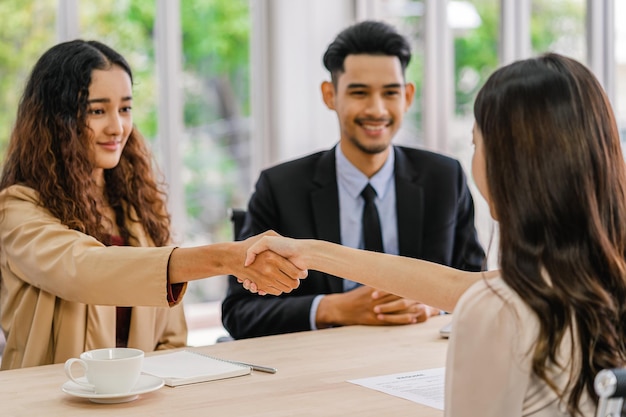 Stretta di mano del primo piano dopo l'accordo del colloquio tra la giovane donna asiatica e due manager