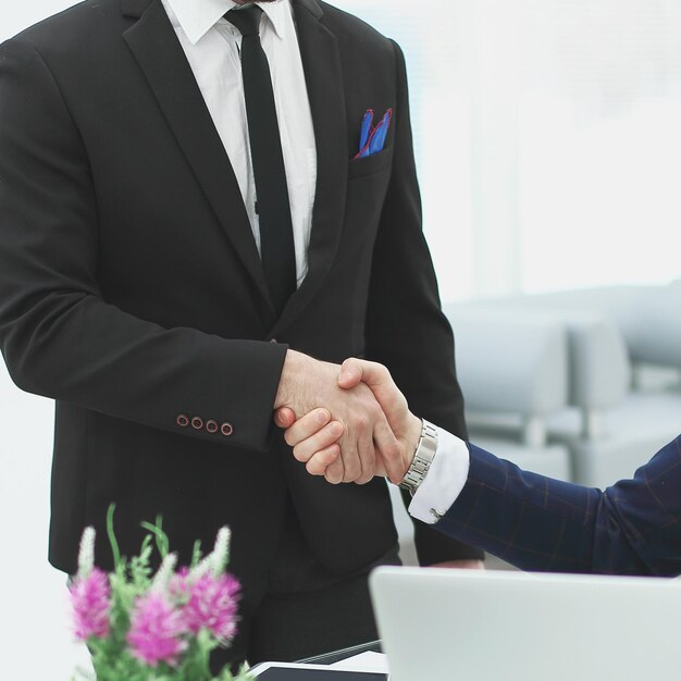 Stretta di mano di due uomini d'affari vicino al tavolo in officephoto con spazio per la copia