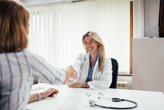 Stretta di mano di medico femminile Smling con un paziente.