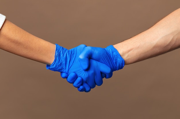 Stretta di mano in guanti blu, concetto di aiuto.