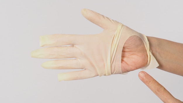 Stretta di mano Indossare guanti medici strappati o guanti di gomma strappati e dito puntato della mano sinistra su sfondo bianco.