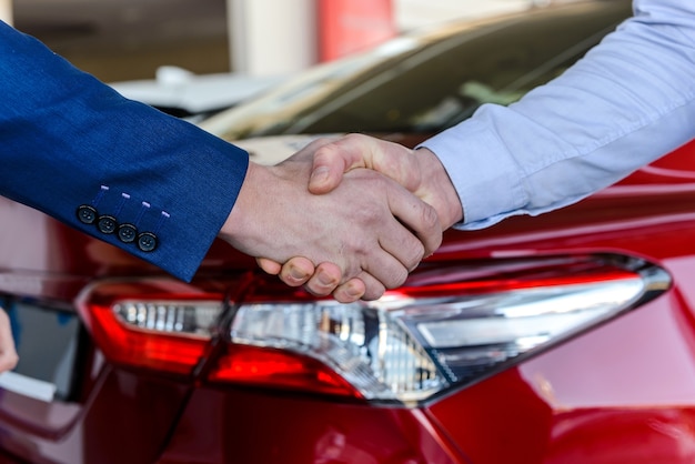 Strette di mano forti su sfondo auto. Affare di acquisto di auto