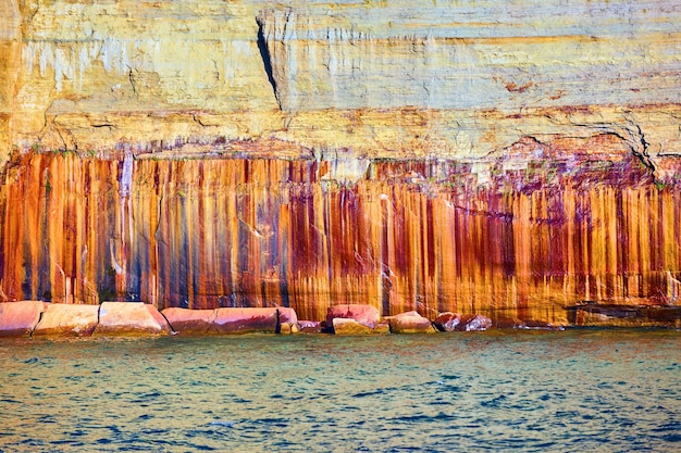 Striature di ferro in Pictured Rocks con pietra rosso ruggine e minerali di oro bianco e colori grigi