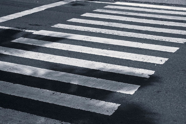 Strisce bianche su strada asfaltata nera per l'incrocio pedonale Un posto per attraversare la strada