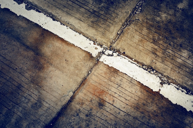 Strisce bianche sul vecchio fondo della strada cementata con colore scuro tonificato e scenetta. Sfondo grunge.