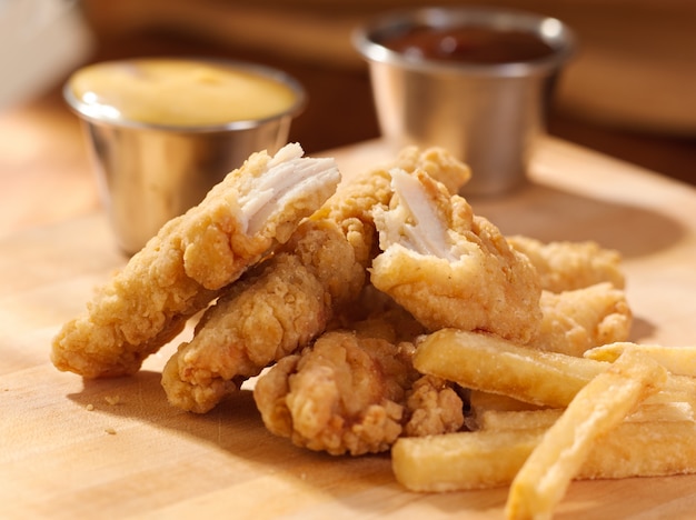 Strisce di pollo fritte con patatine fritte e salsa