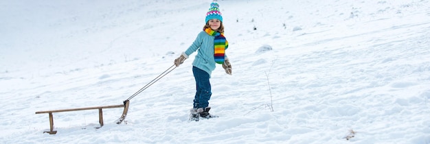 Striscione invernale bambino slittino nella foresta innevata invernale bambini con slitta slitta nella neve invernale banner