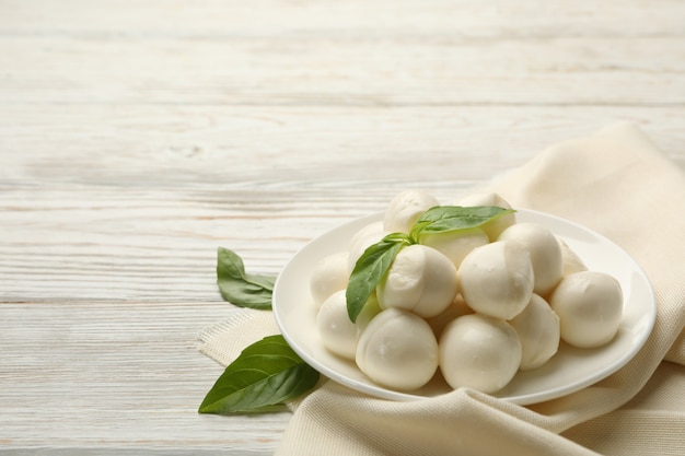 Strofinaccio da cucina con piastra con mozzarella e basilico su fondo in legno