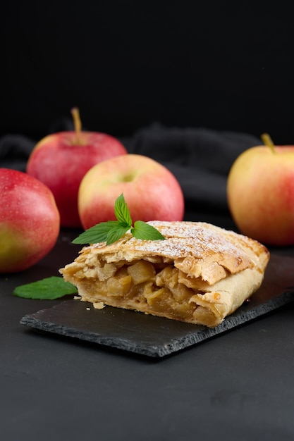 Strudel al forno con mele cosparse di zucchero a velo su una tavola nera