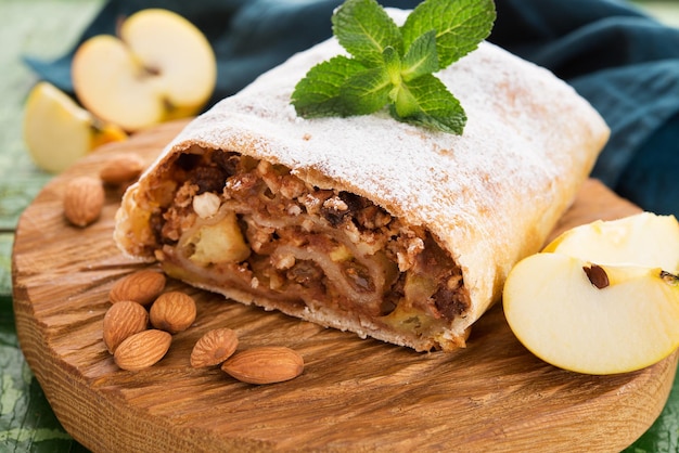 Strudel di mele con noci e uvetta su una tavola di legno, primo piano