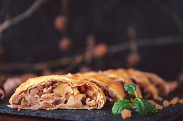 Strudel di mele, uvetta e noci in stile rustico su fondo scuro