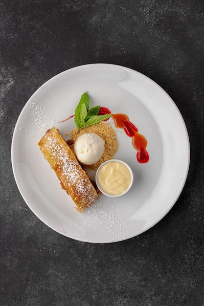 Strudel dolce con mele gelato alla menta e latte condensato su fondo scuro