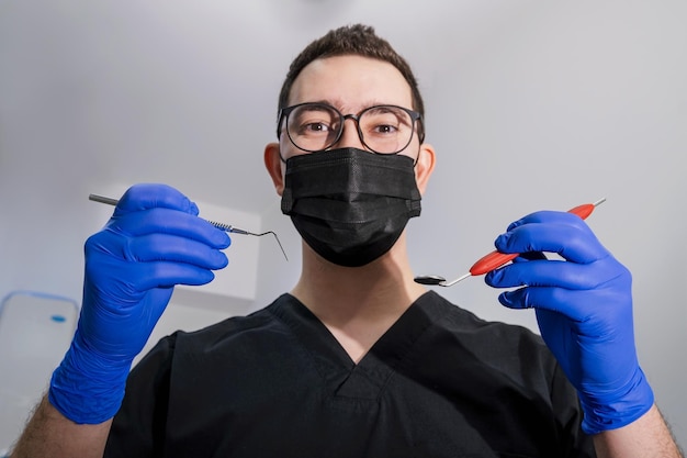 strumenti dentali nelle mani del medico. dentista in guanti di lattice sterili che tengono strumenti dentali
