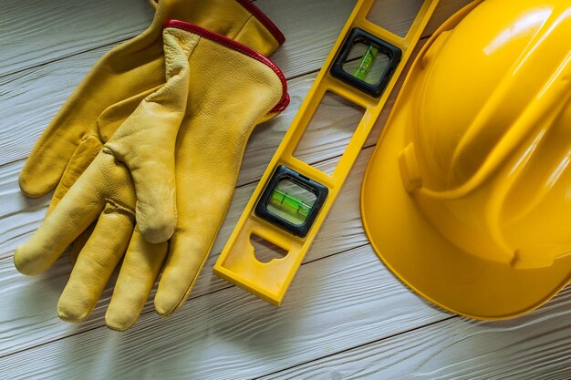 Strumenti di costruzione livello del casco giallo e guanti da lavoro su tavole di legno bianche dipinte di wvintage