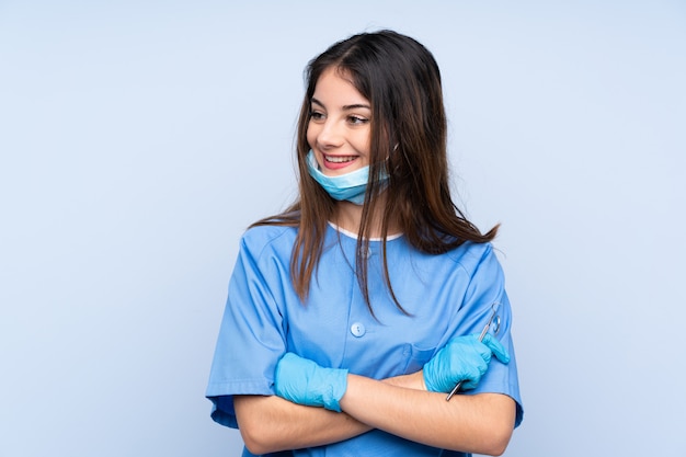 Strumenti di tenuta del dentista della donna sopra la parete blu