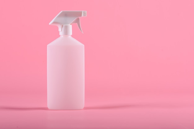 Strumenti per la pulizia. Flacone spray isolato su sfondo rosa.