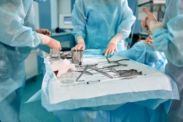 Strumenti sterili sul tavolo operatorio, un team di medici dispone gli strumenti per l'operazione. molte mani stanno fermentando in guanti sterili.