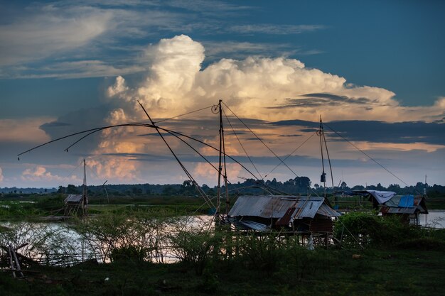 Strumento di pesca tradizionale o trappola per pesci di bambù sulla luce del tramonto, silhouette del paesaggio.