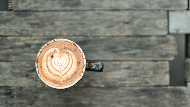 Struttura del cuore del latte del caffè sul pavimento di legno.