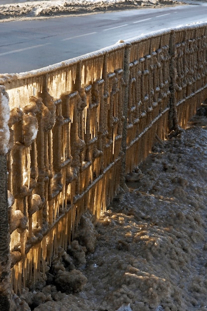 Struttura del trasporto della città invernale - guardrail autostradale glassato (dalla granita dell'autostrada) e luce solare attraverso i ghiaccioli