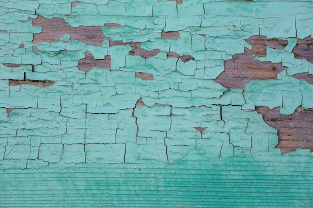 Struttura della parete di una casa in legno con vernice verde scrostata in una giornata di sole Sfondo turchese