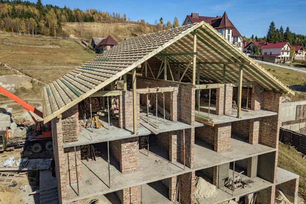 Struttura di legno di nuovo tetto su una grande casa del mattone in costruzione.