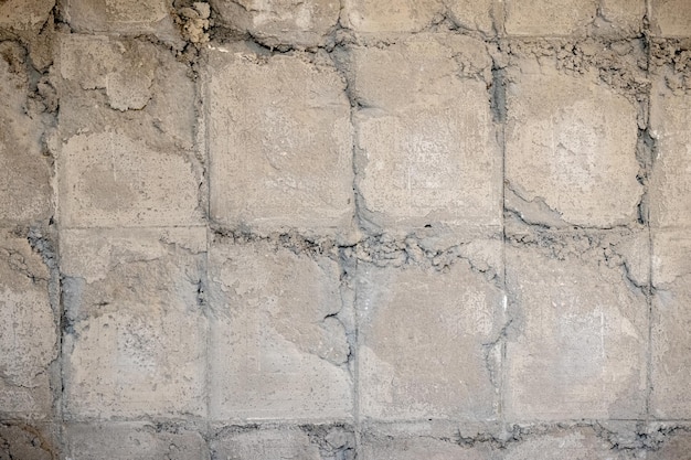 Struttura di un muro di cemento grigio con tracce di piastrelle di rivestimento smantellate