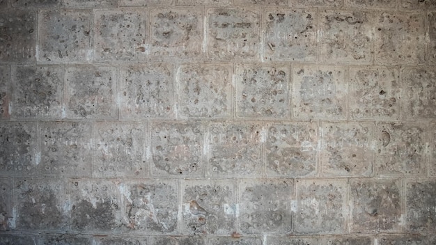Struttura di un muro di cemento grigio con tracce di piastrelle di rivestimento smantellate