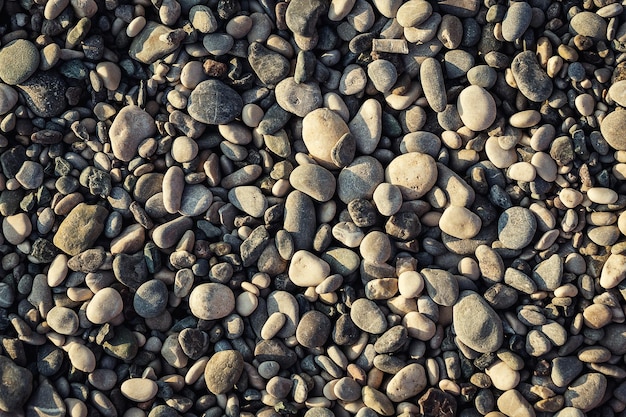 Struttura grigia della spiaggia delle pietre del ciottolo sul mare come fondo