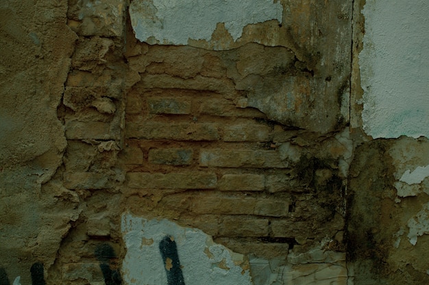 Struttura in mattoni a vista su un vecchio muro danneggiato con intonaco mancante incrinato