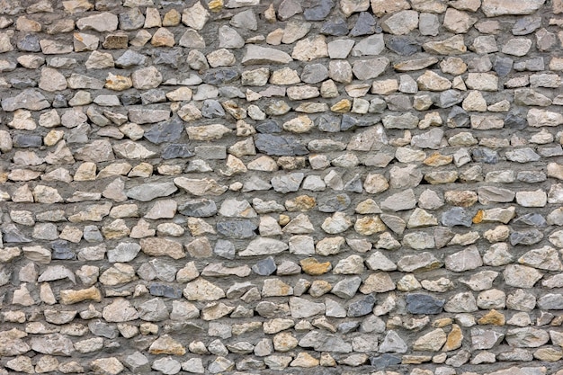 Struttura senza cuciture e sfondo piatto full frame di brutto muro di pietra tagliente con cemento tra le rocce