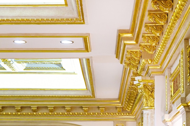 Stucco decorativo in oro sul soffitto in interni lussuosi e costosi di un grande soggiorno reale barocco