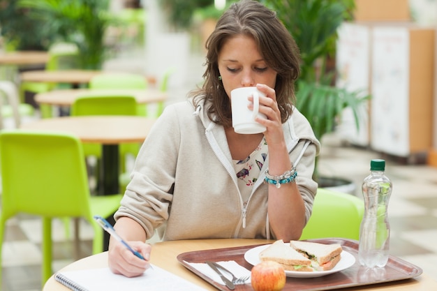 Studente a fare i compiti e fare colazione in mensa