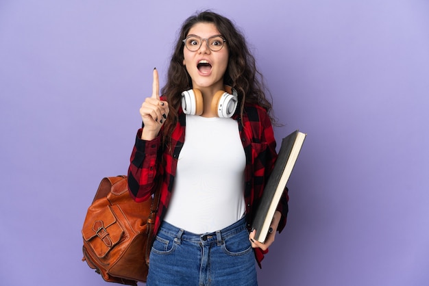 Studente adolescente isolato sul muro viola che intende realizzare la soluzione alzando un dito