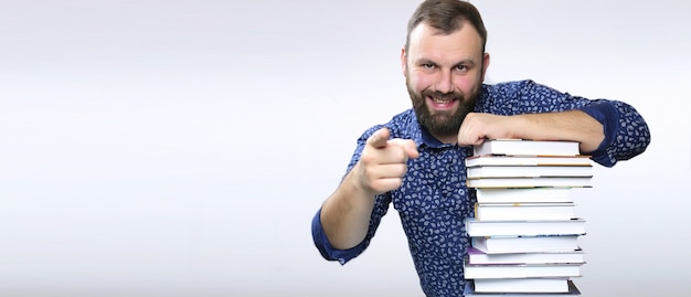 Studente adulto barba uomo con pila di libri in una biblioteca