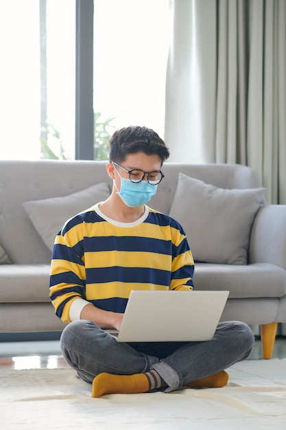 Studente asiatico con molti libri e laptop che si prepara per l'esame a casa