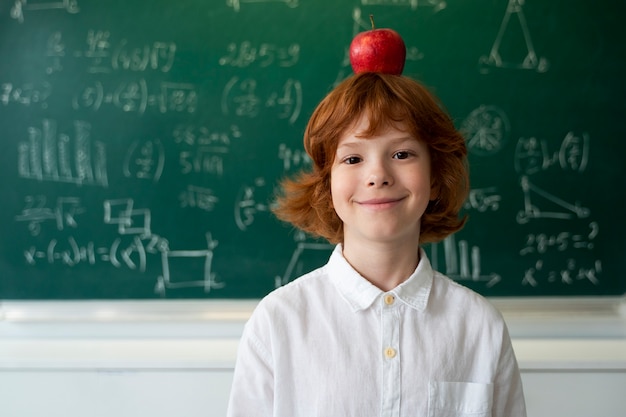 Studente bambino a scuola con la mela sulla testa