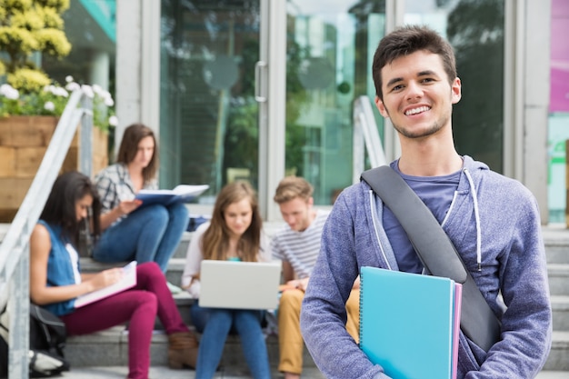 Studente bello che sorride alla macchina fotografica fuori