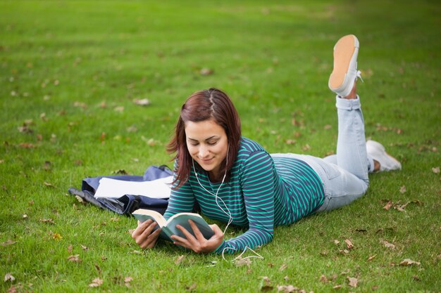 Studente casuale contento che si trova sulla lettura dell&#39;erba