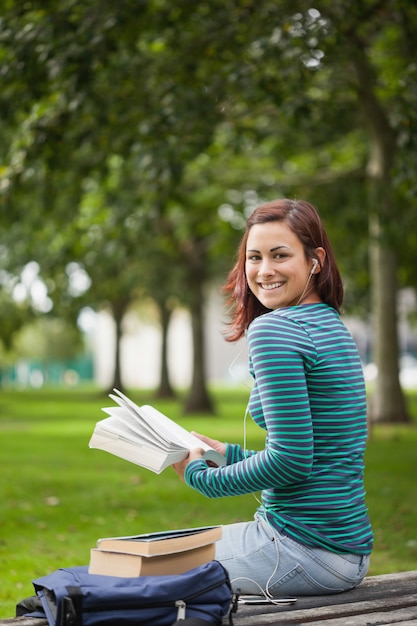 Studente casuale felice che si siede sulla lettura del banco