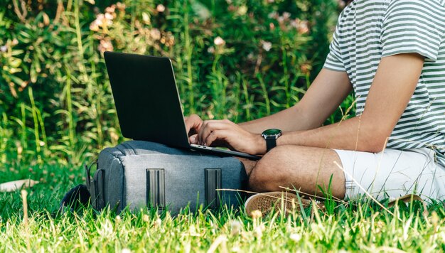 Studente caucasico irriconoscibile che utilizza un computer portatile in un parco