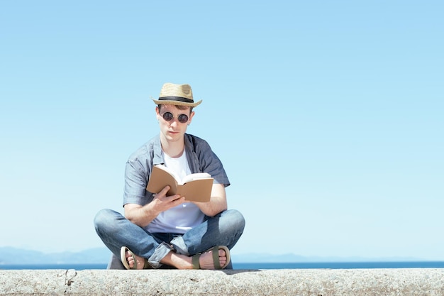 Studente che legge un libro in estate. Studiare all'aperto concetto.