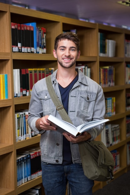 Studente che sorride alla macchina fotografica in biblioteca